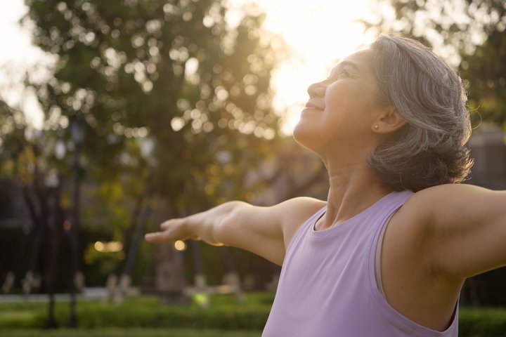 Ältere Frau, die draussen Yoga übt