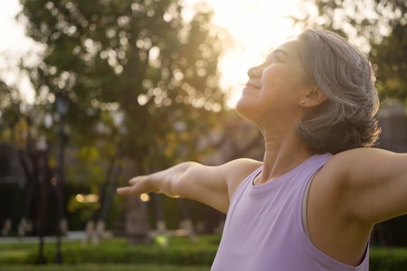 Ältere Frau, die draussen Yoga übt
