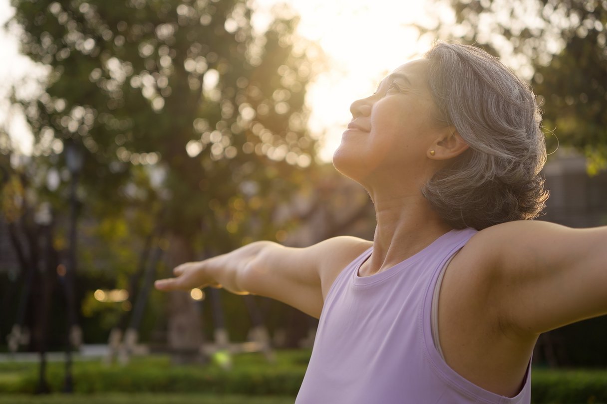 Ältere Frau, die draussen Yoga übt
