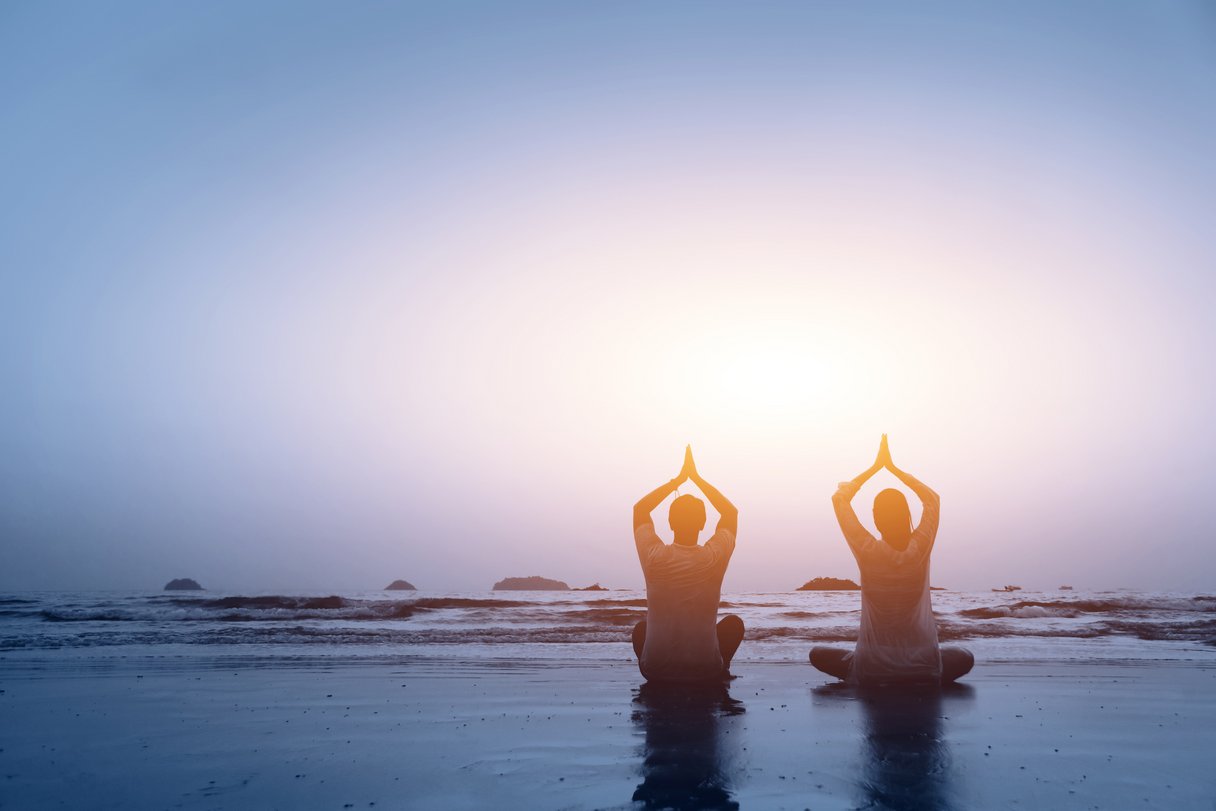 Yoga-Paar bei Sonnenuntergang am Strand